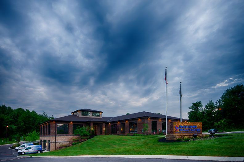A large building with a sign in front of it and a cloudy sky in the background.