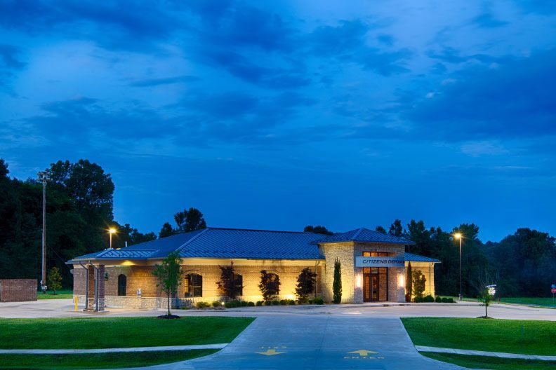 A large building with a blue roof is lit up at night.