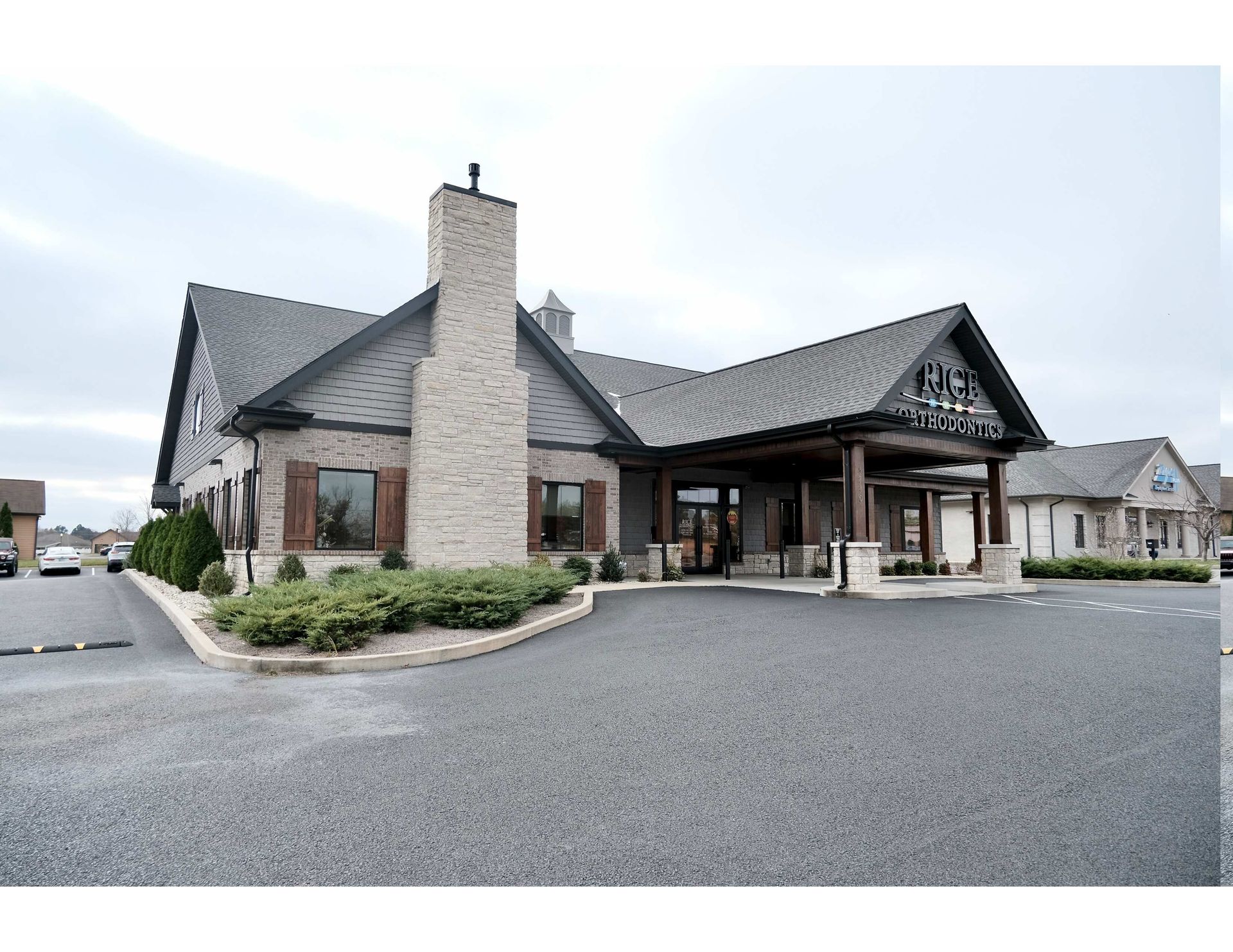 A large building with a lot of windows is surrounded by grass and trees.
