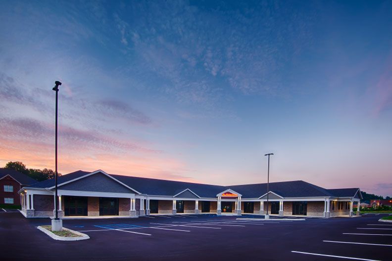 A large building with a parking lot in front of it at sunset.