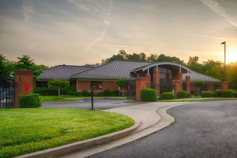 A large brick building with a metal roof is sitting on top of a lush green field.