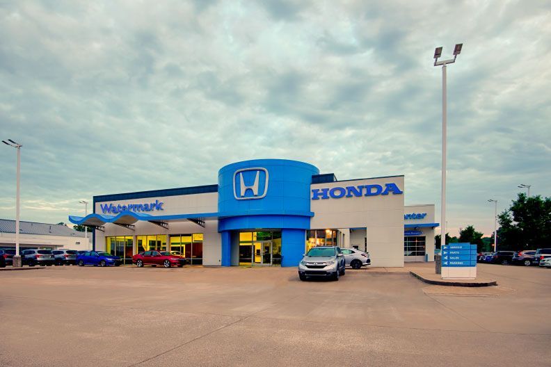 A honda dealership with cars parked in front of it