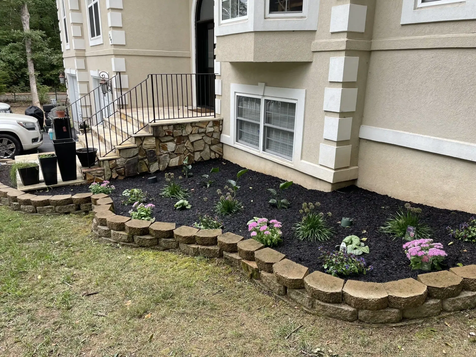 A garden in front of a house with flowers and mulch.