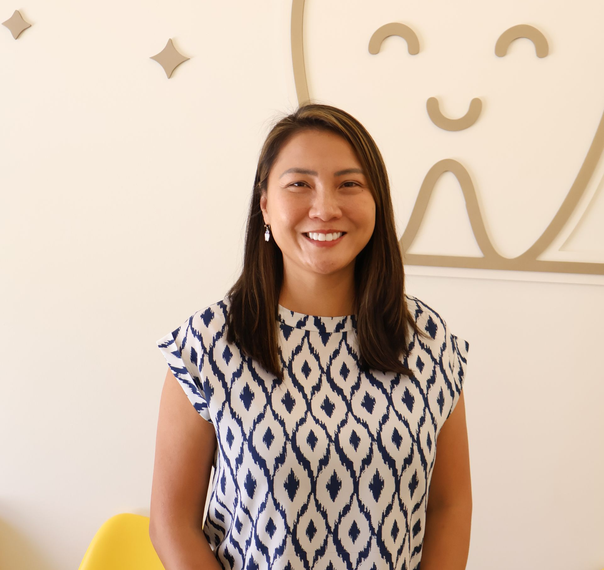 A woman wearing a printed blouse and is smiling for the camera.