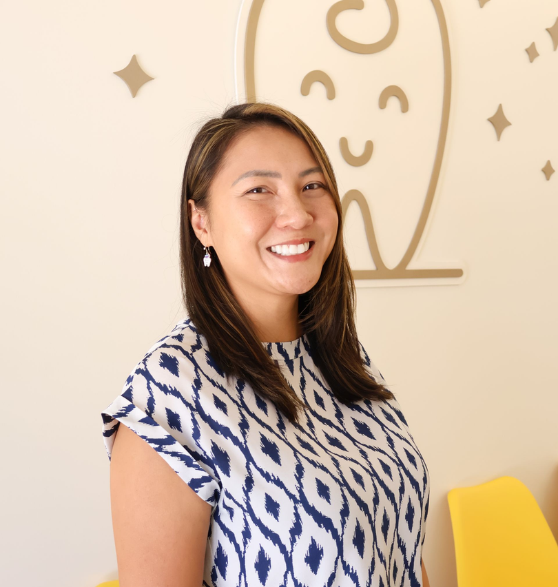 A woman wearing a printed blouse and is smiling for the camera.