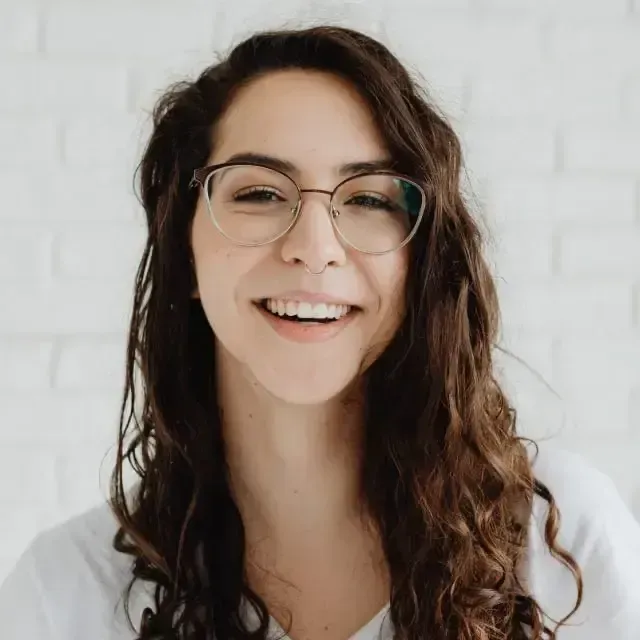 A woman wearing glasses and a white shirt is smiling