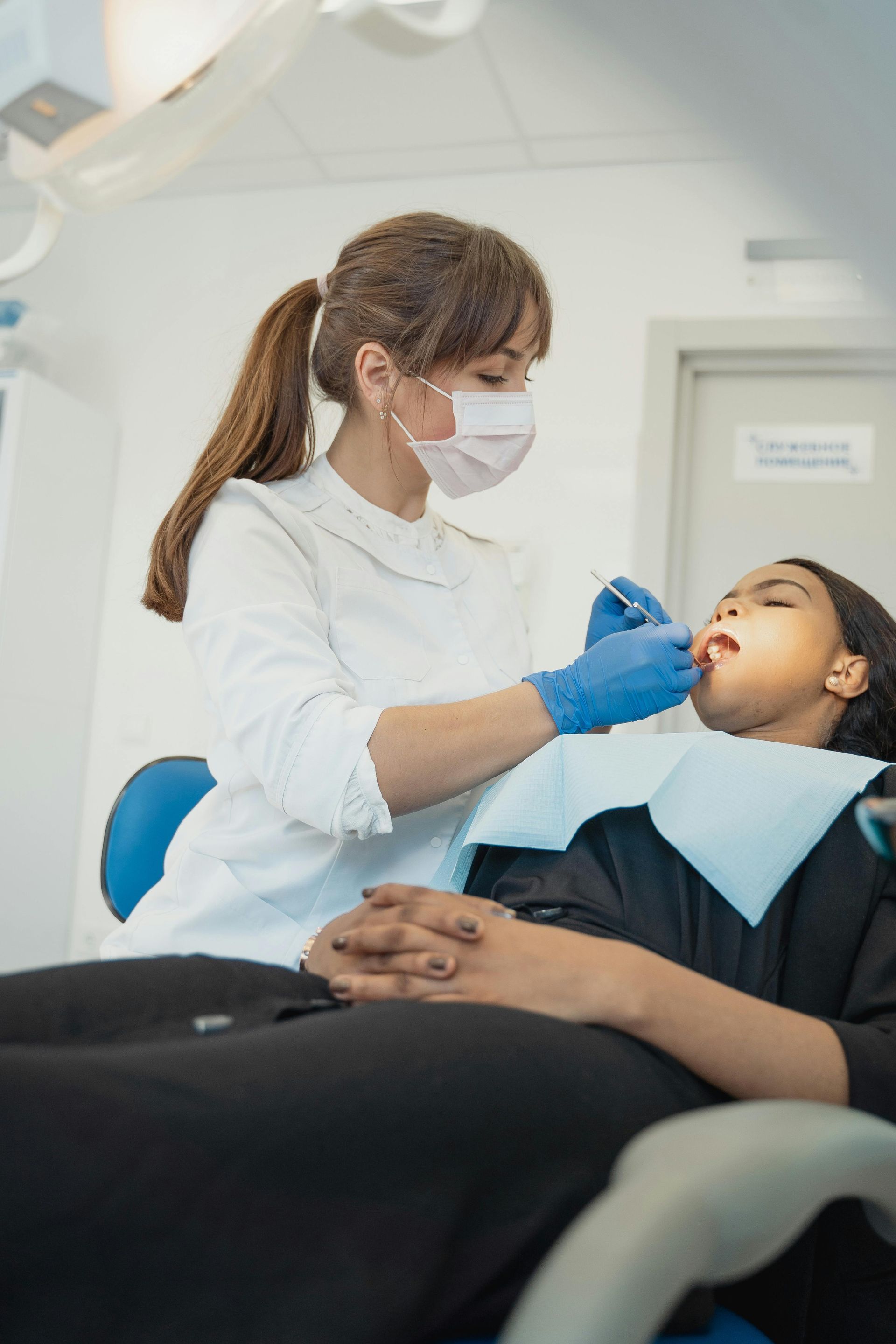 A little boy is getting his teeth examined by a dentist and a nurse.