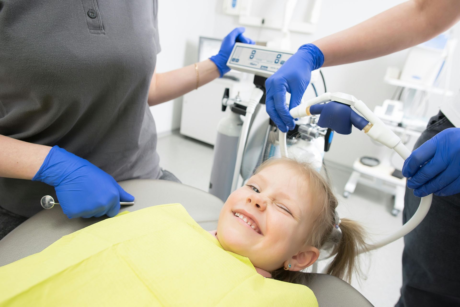 A little boy is getting his teeth examined by a dentist and a nurse.