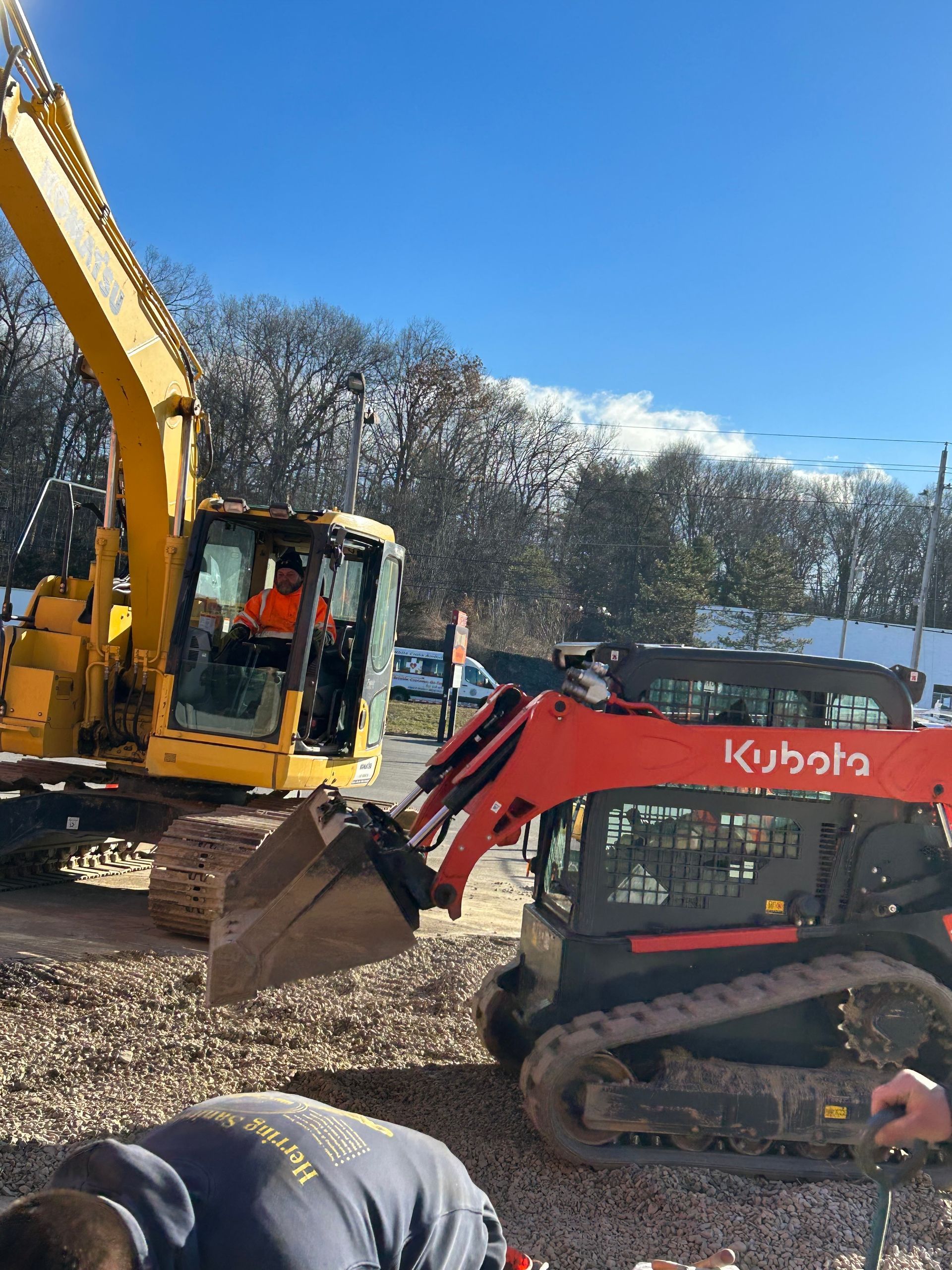 A man is working on a construction site next to a yellow and red excavator.