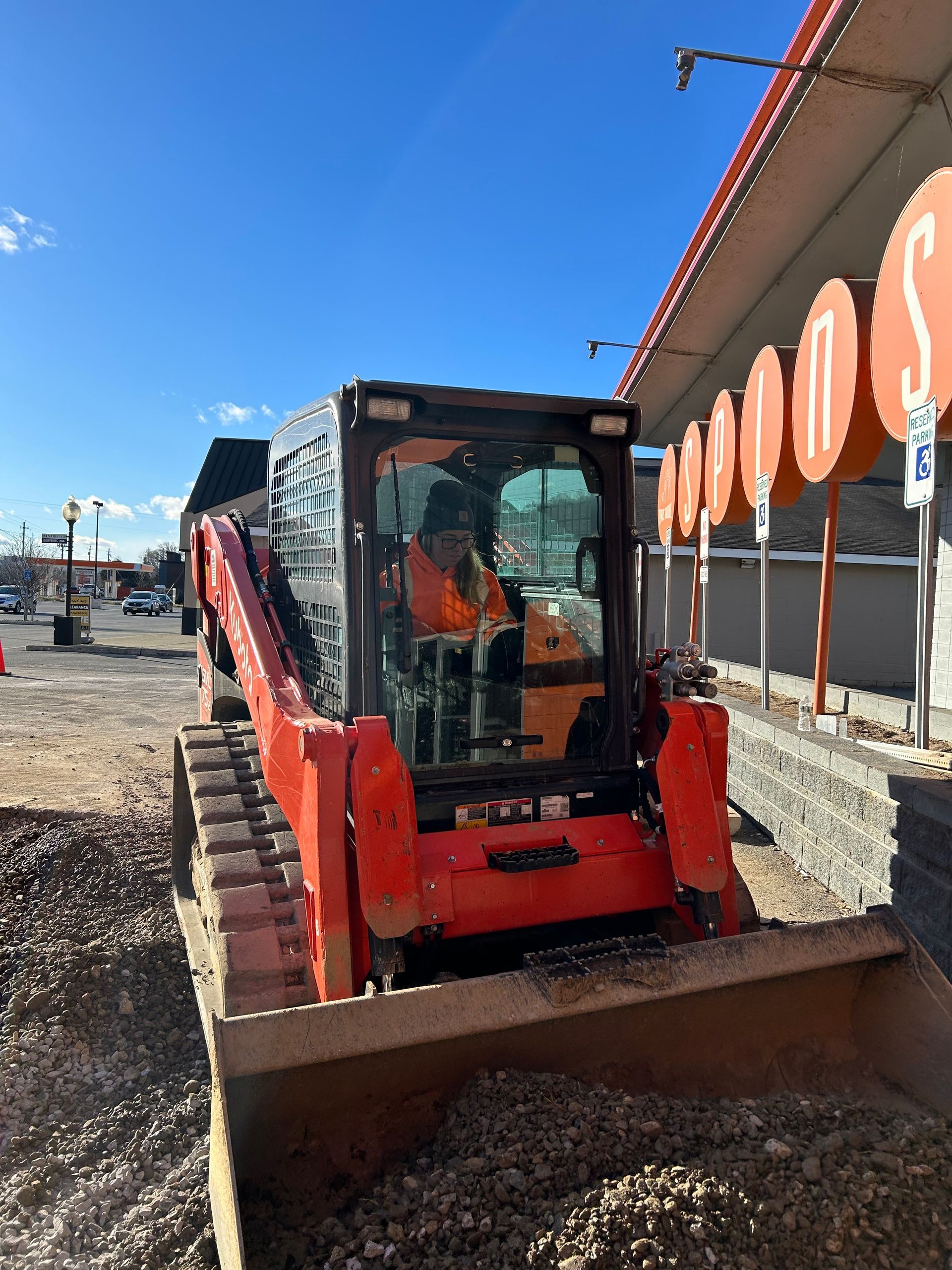 A man is driving a bulldozer in front of a store.