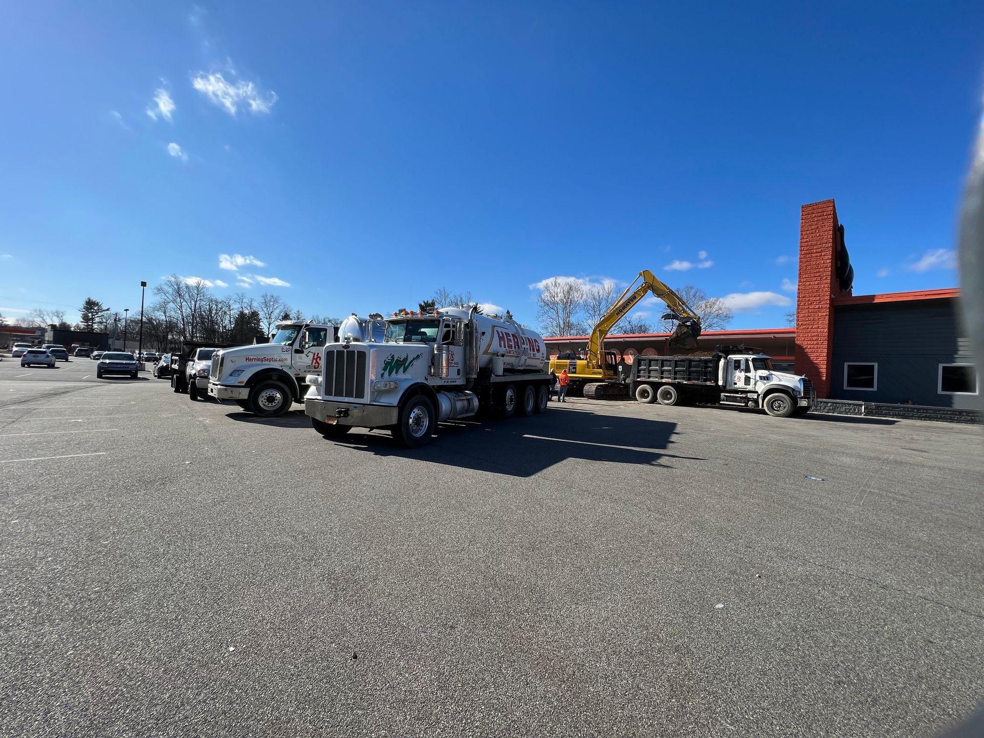A row of trucks are parked in a parking lot in front of a building.