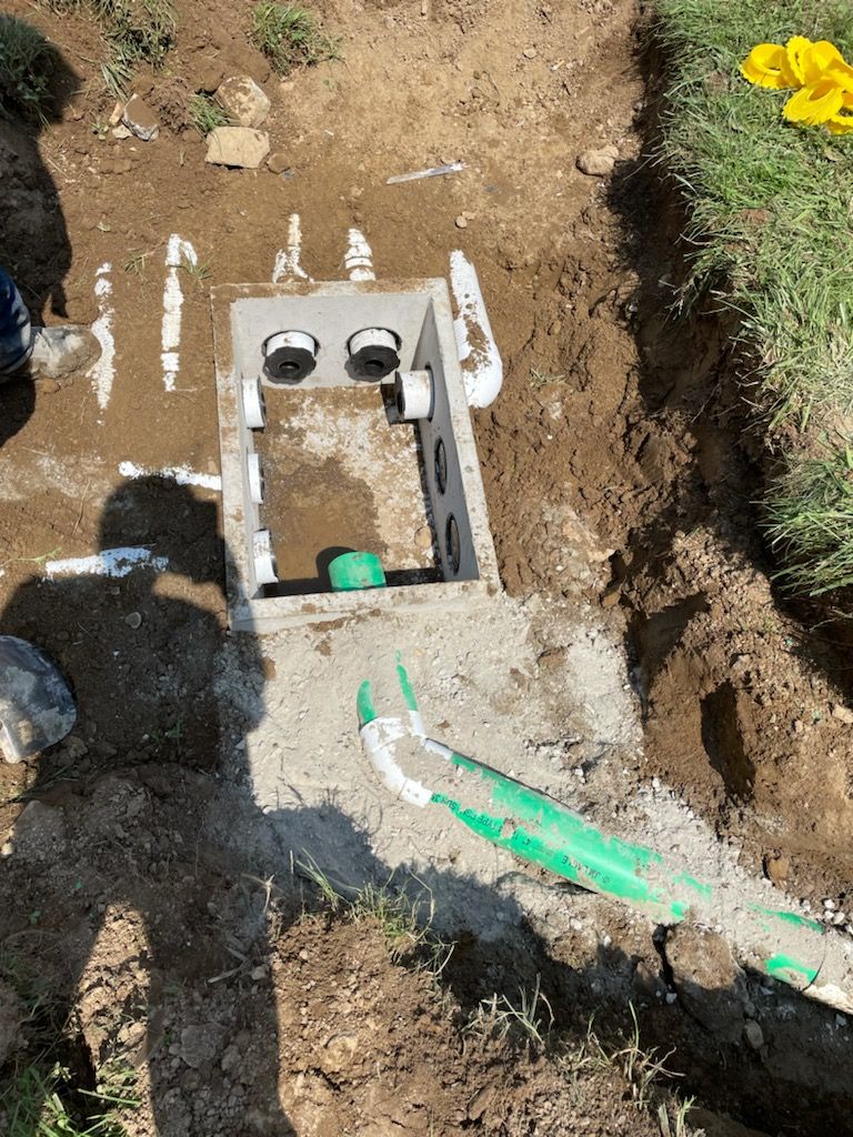 A man is digging a hole in the ground to install a septic tank.