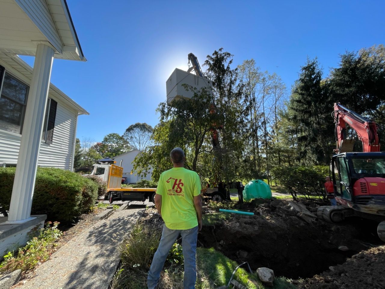 A man in a neon yellow shirt is standing in front of a house.