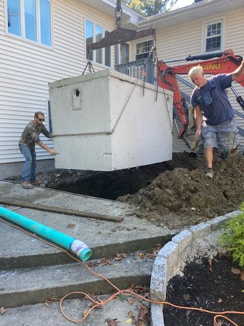 Two men are working on a septic tank in front of a house
