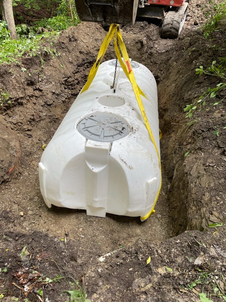 A large white tank is being lifted out of the ground by a bulldozer.