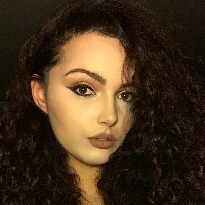 A close up of a woman 's face with curly hair.