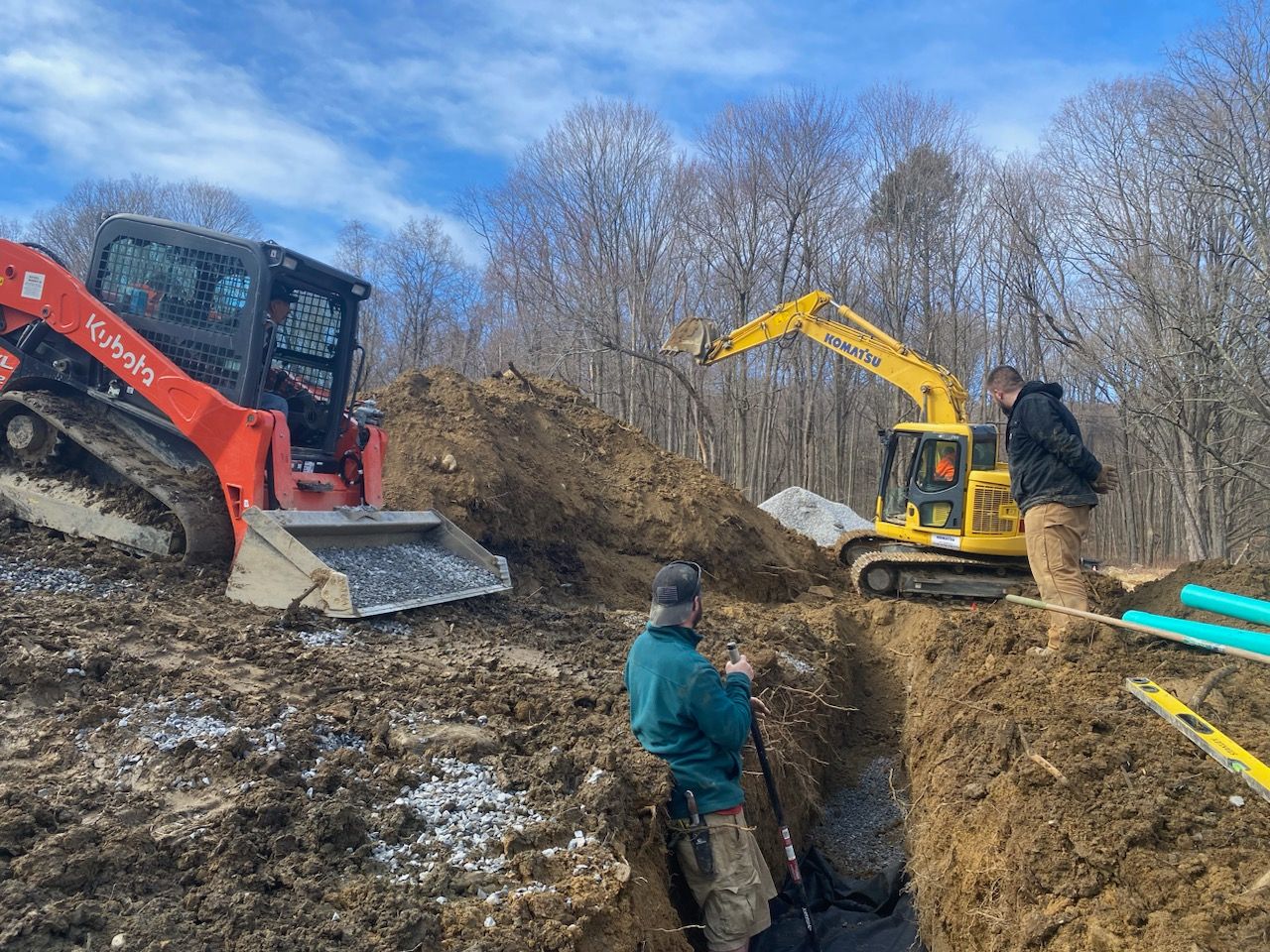 A man is standing next to a bulldozer in a dirt field.
