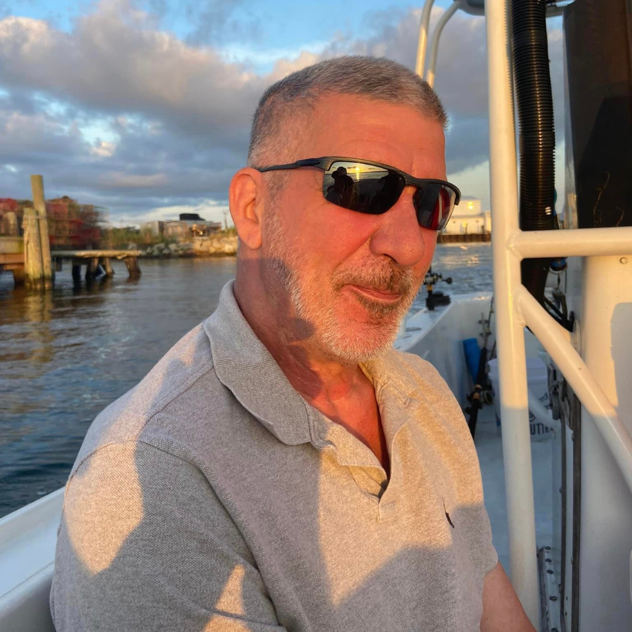 A man wearing sunglasses is sitting on a boat