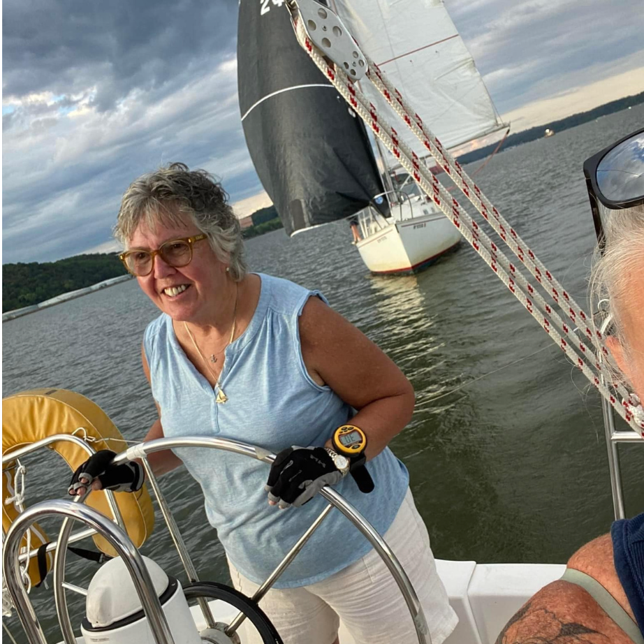 A woman is steering a sailboat in the water.
