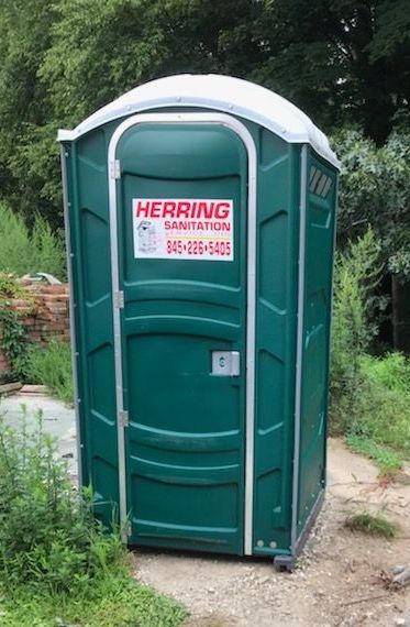 A green portable toilet with a herring sanitation sign on it