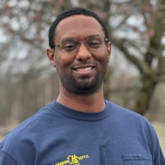 A man wearing a blue t-shirt with a yellow logo on it