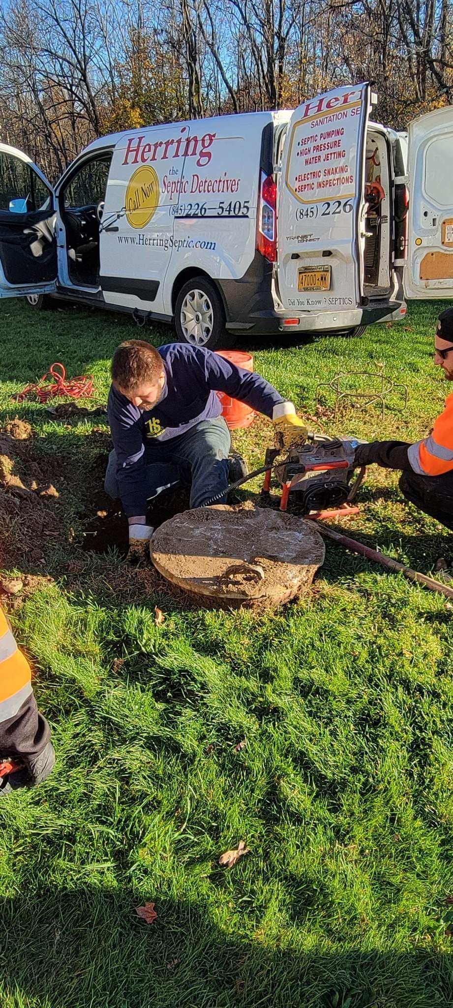 A group of people are working on a tree stump in a field.