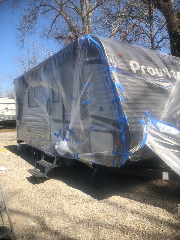 A trailer is wrapped in plastic and painted blue.