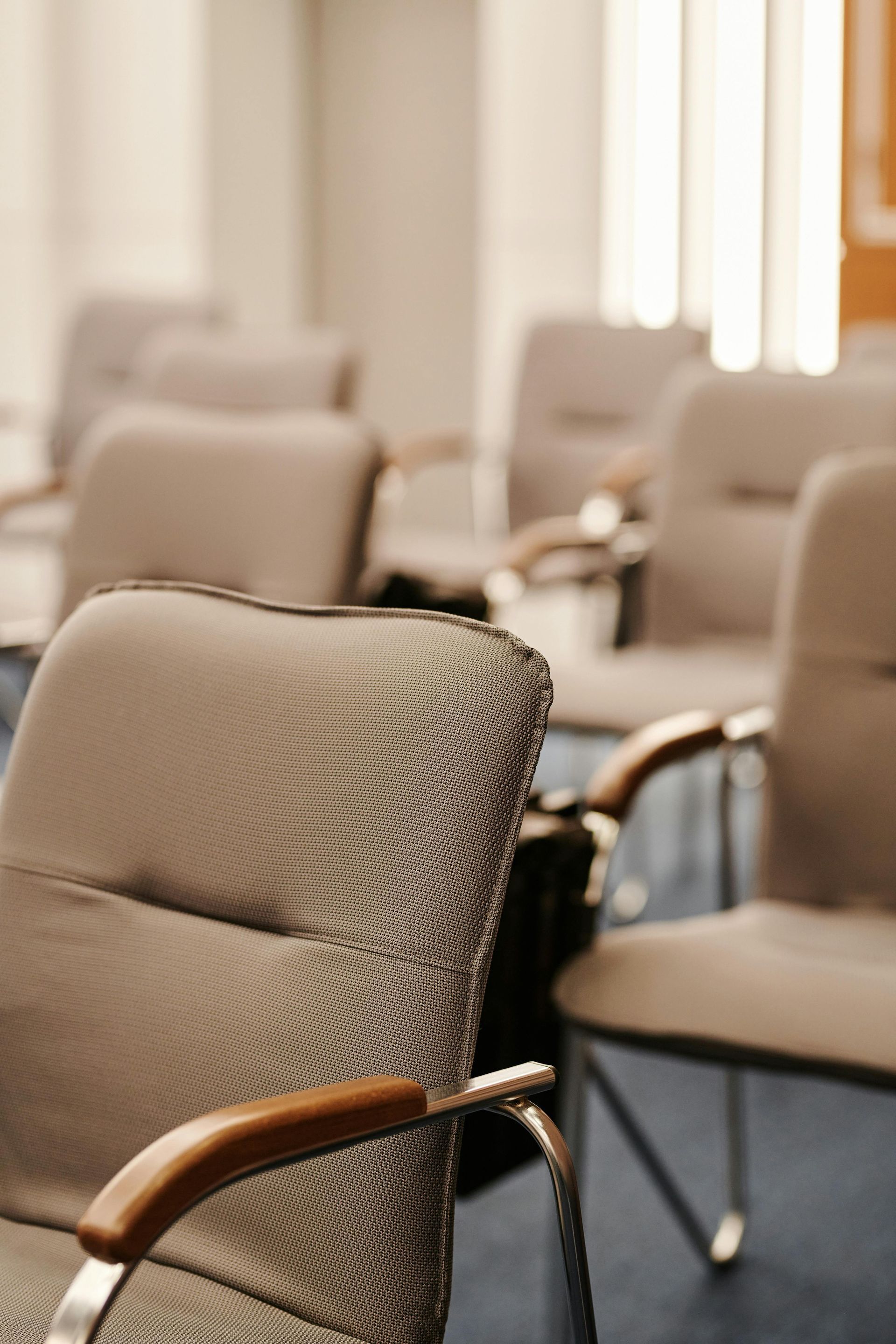 Empty beige upholstered chairs in a conference or waiting room with blue carpet