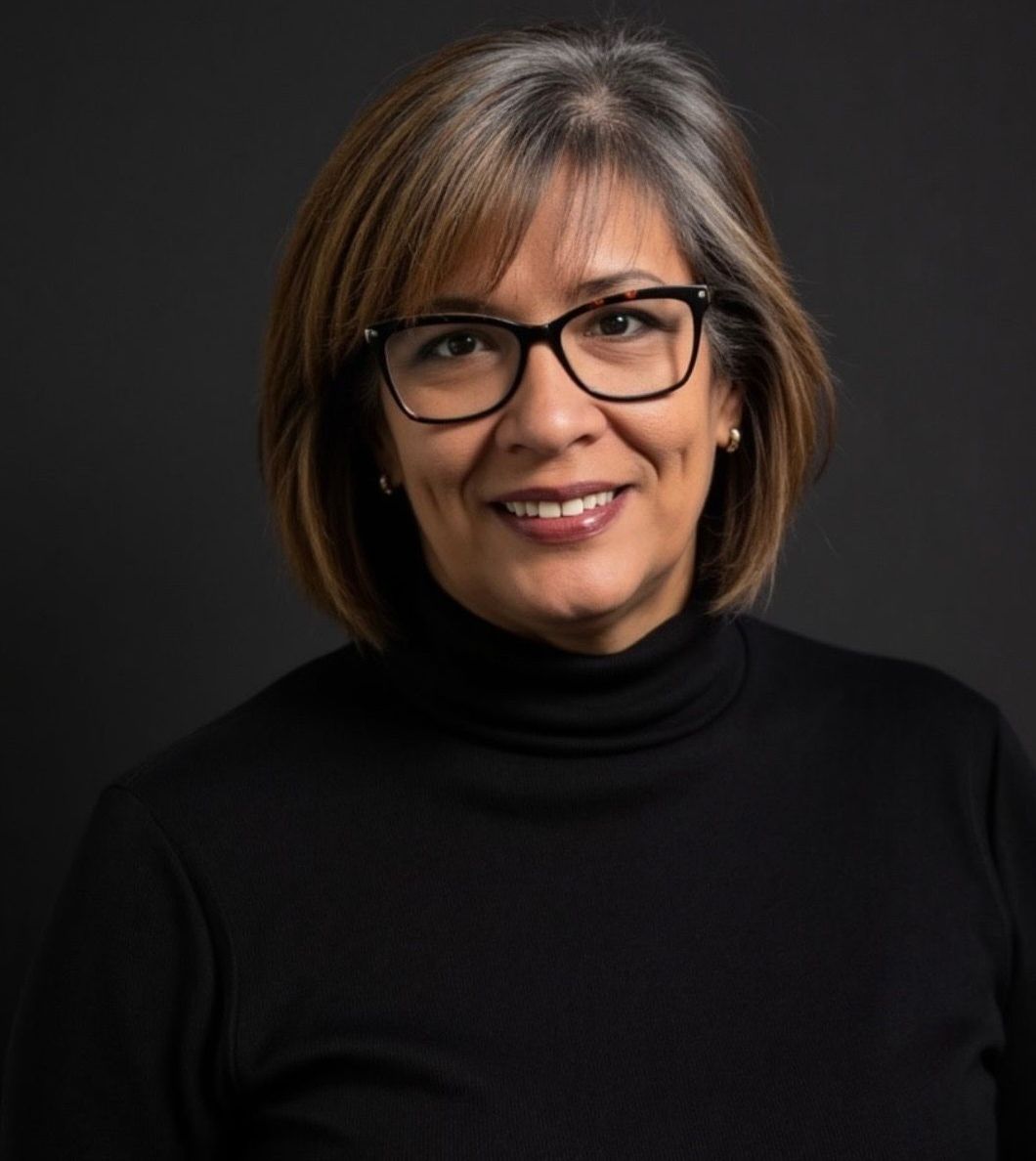 Woman with glasses and a black turtleneck smiles.