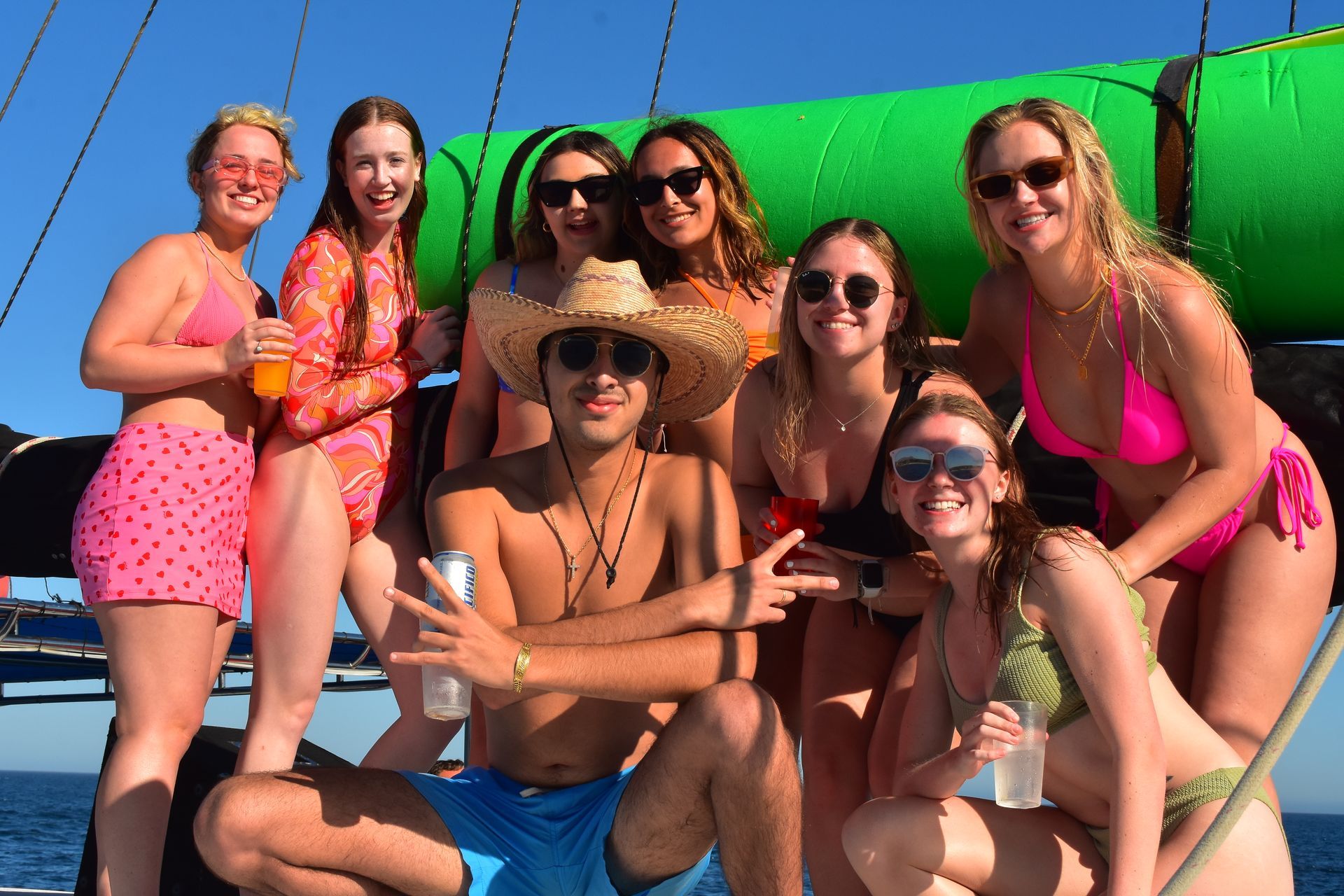 A group of people in bikinis are posing for a picture on a boat.
