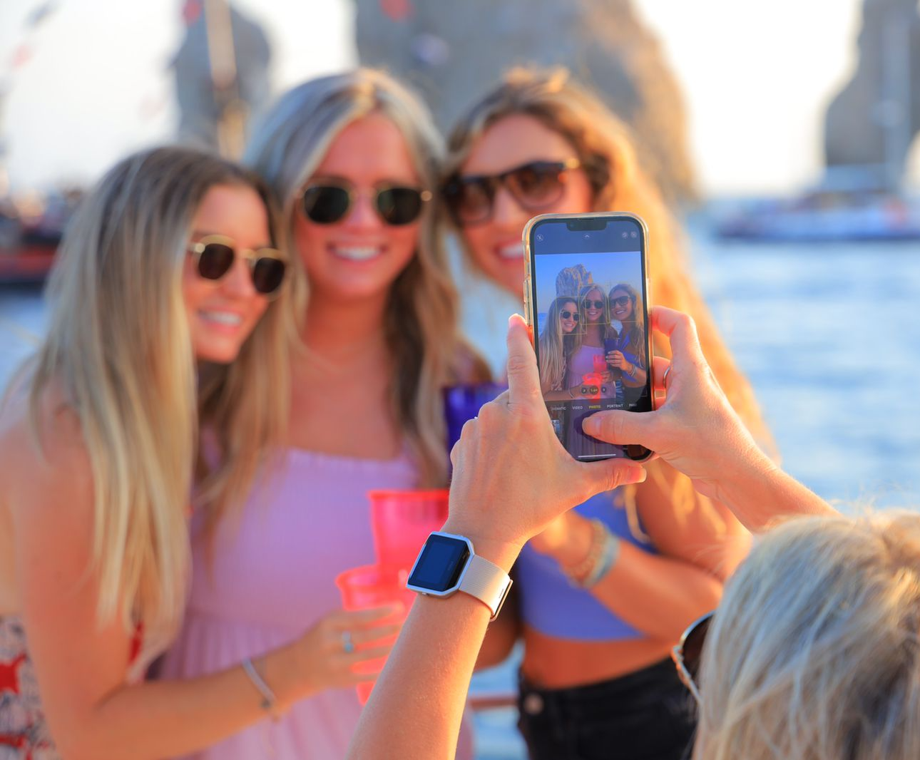 A woman is taking a picture of three women on a boat