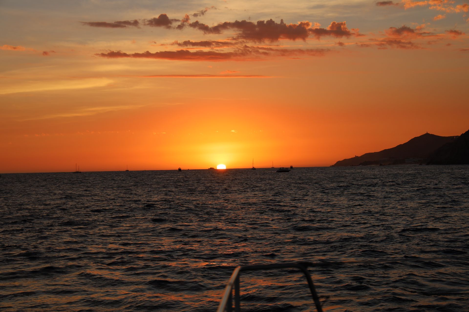 El sol se pone sobre el océano con un barco en la distancia.