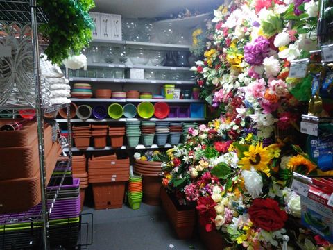 esposizione di vasi per piante, sottovasi e fiori finti di vario colore e di diversa dimensione
