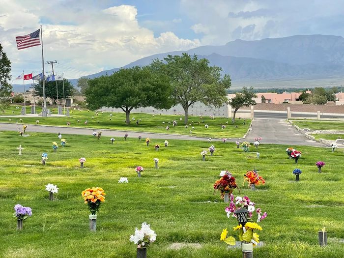 Rendering of a memorial with a central cross and surrounding structures, trees, and sky.