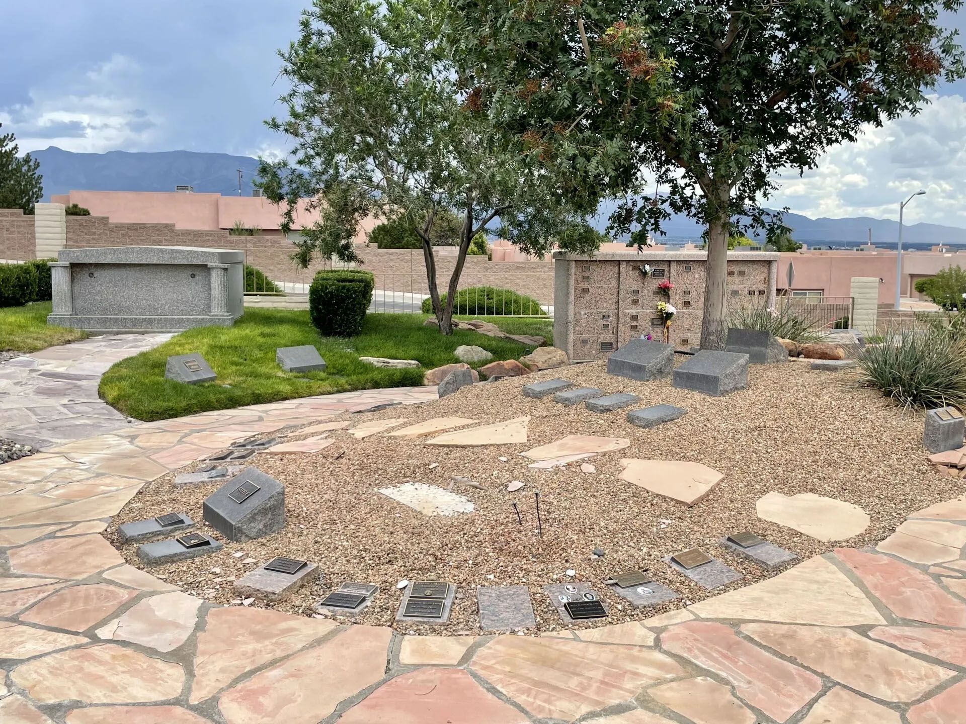Aerial view of a green park with trees and roads. Cars are parked near the entrance.
