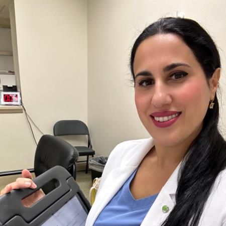 A woman in a lab coat is smiling and holding a tablet