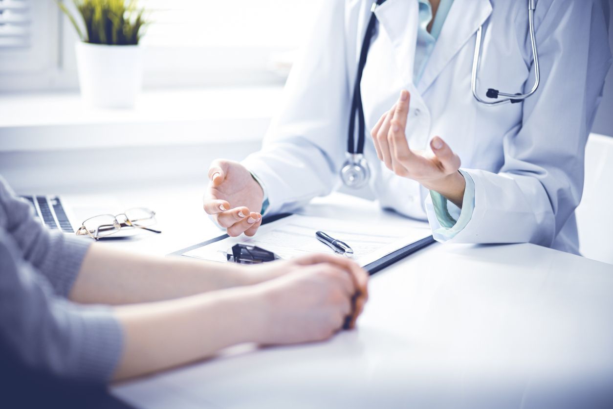A doctor is talking to a patient at a desk.