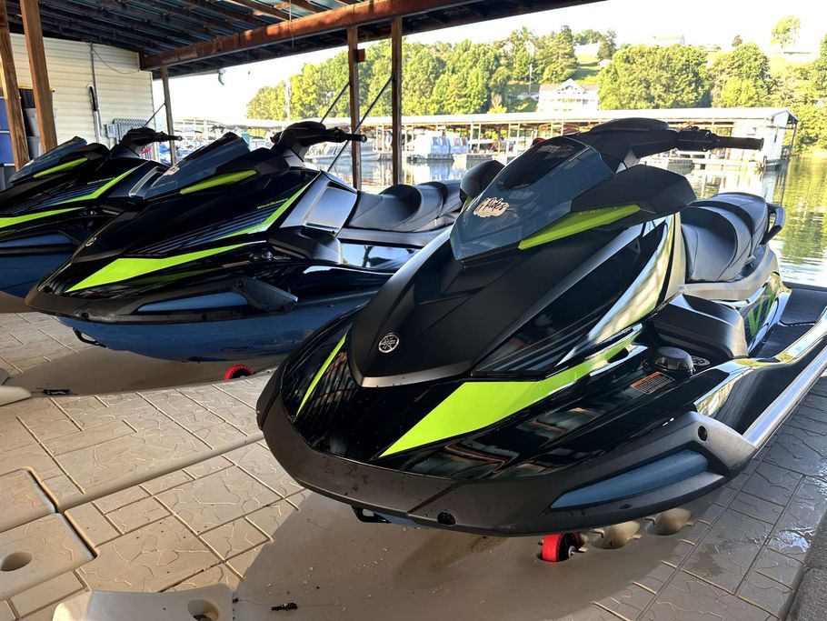 Two jet skis are parked on a dock near a body of water