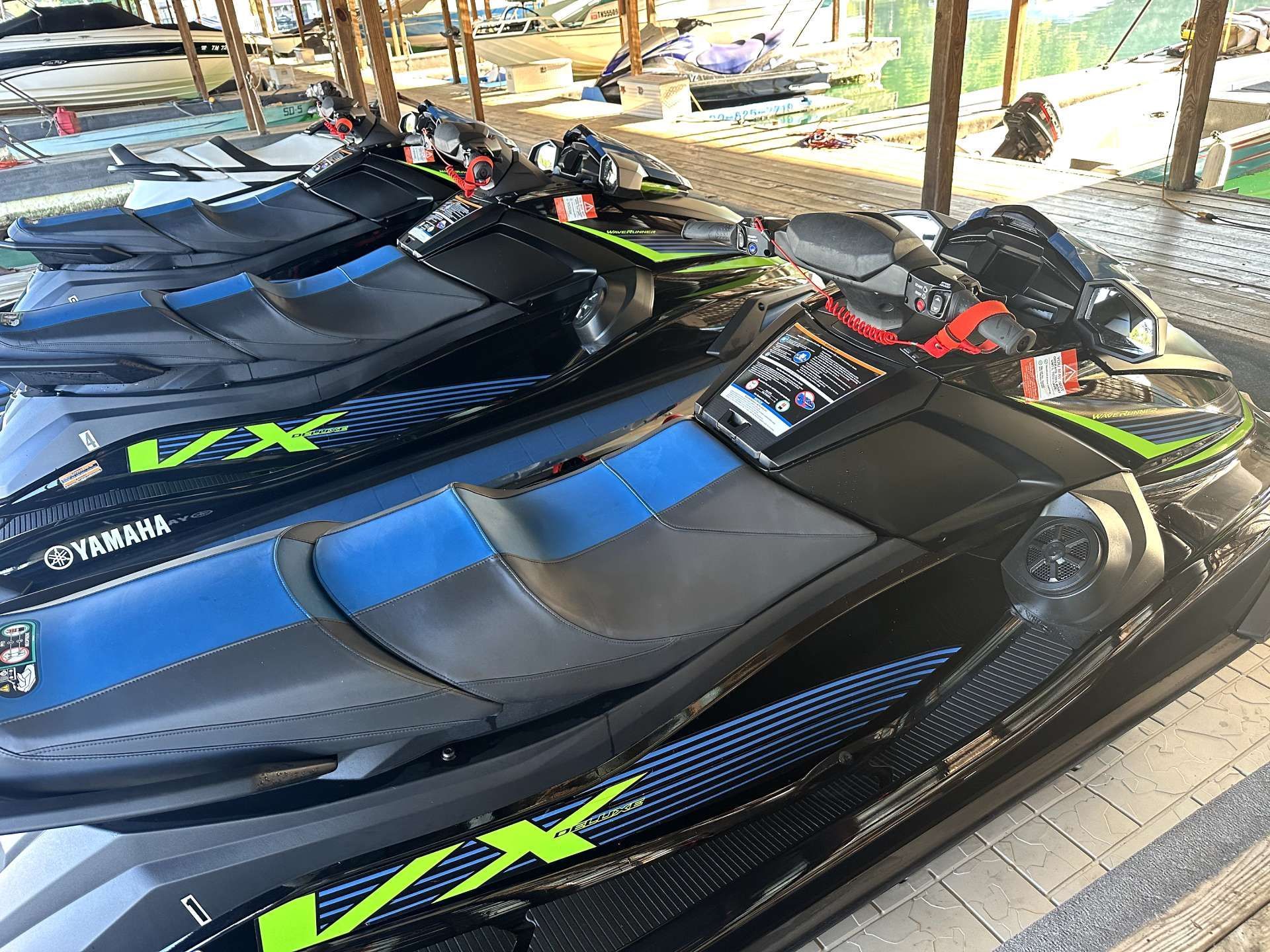 A row of jet skis are parked under a canopy