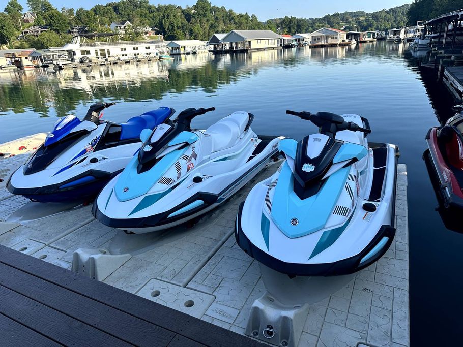 Three jet skis are parked on a dock near the water