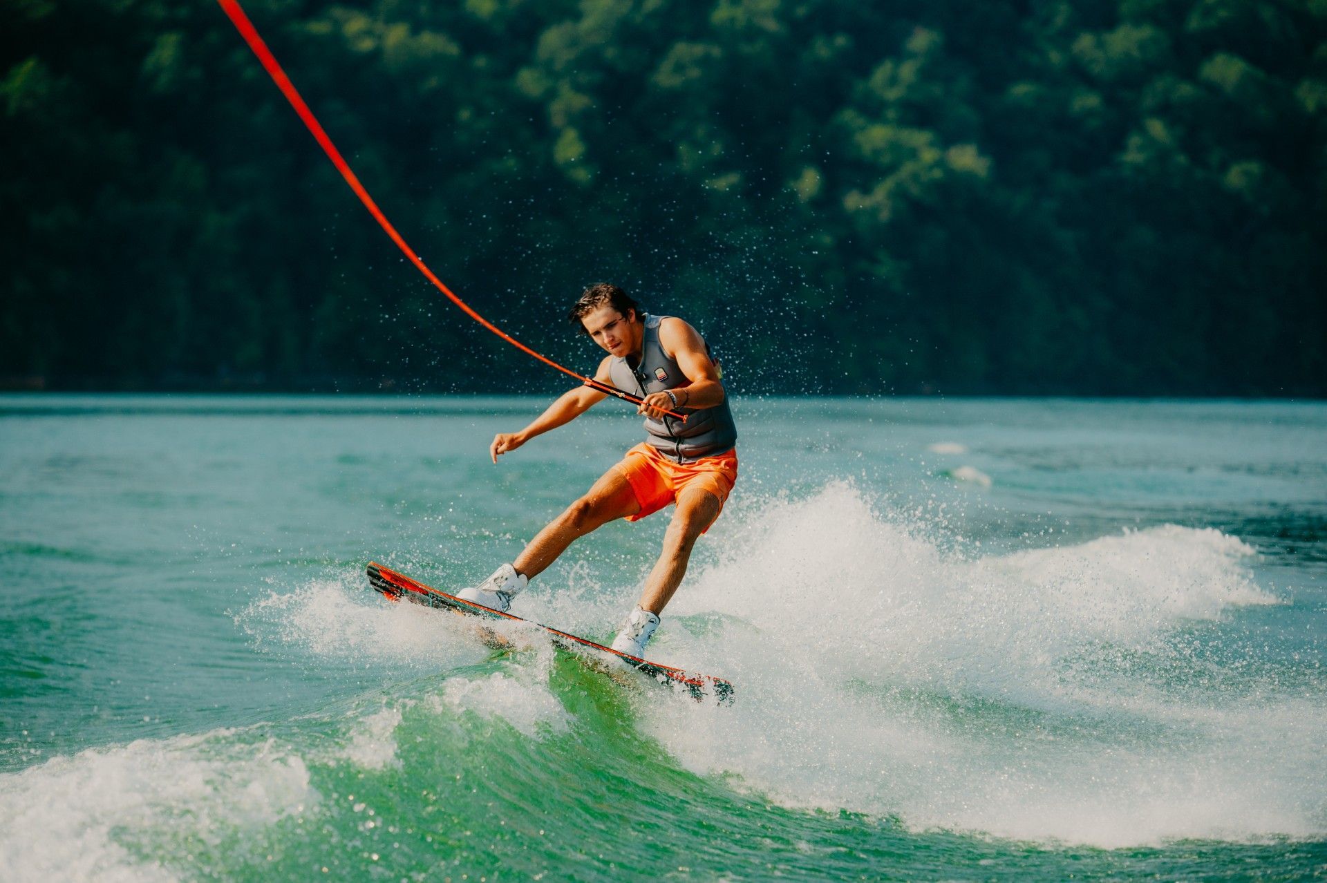 A man is water skiing on a lake with trees in the background