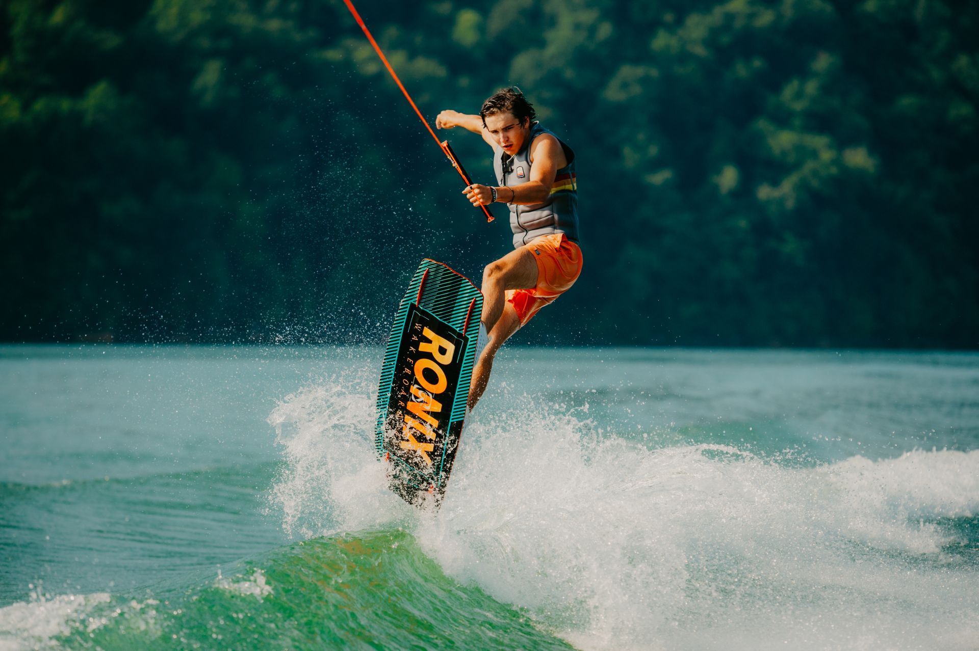 A person is riding a wave on a board that says ronix