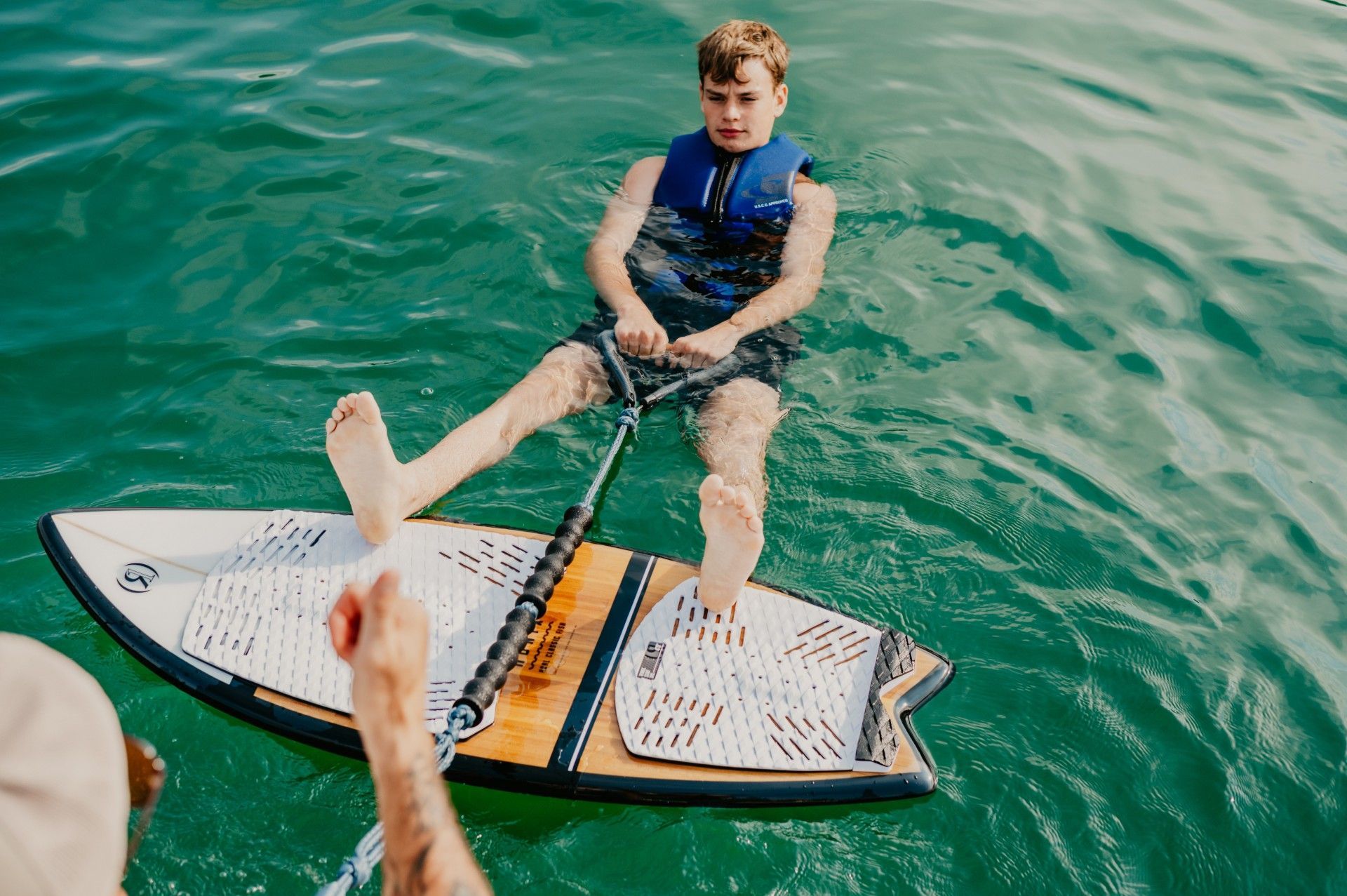 A boy is sitting on a surfboard in the water