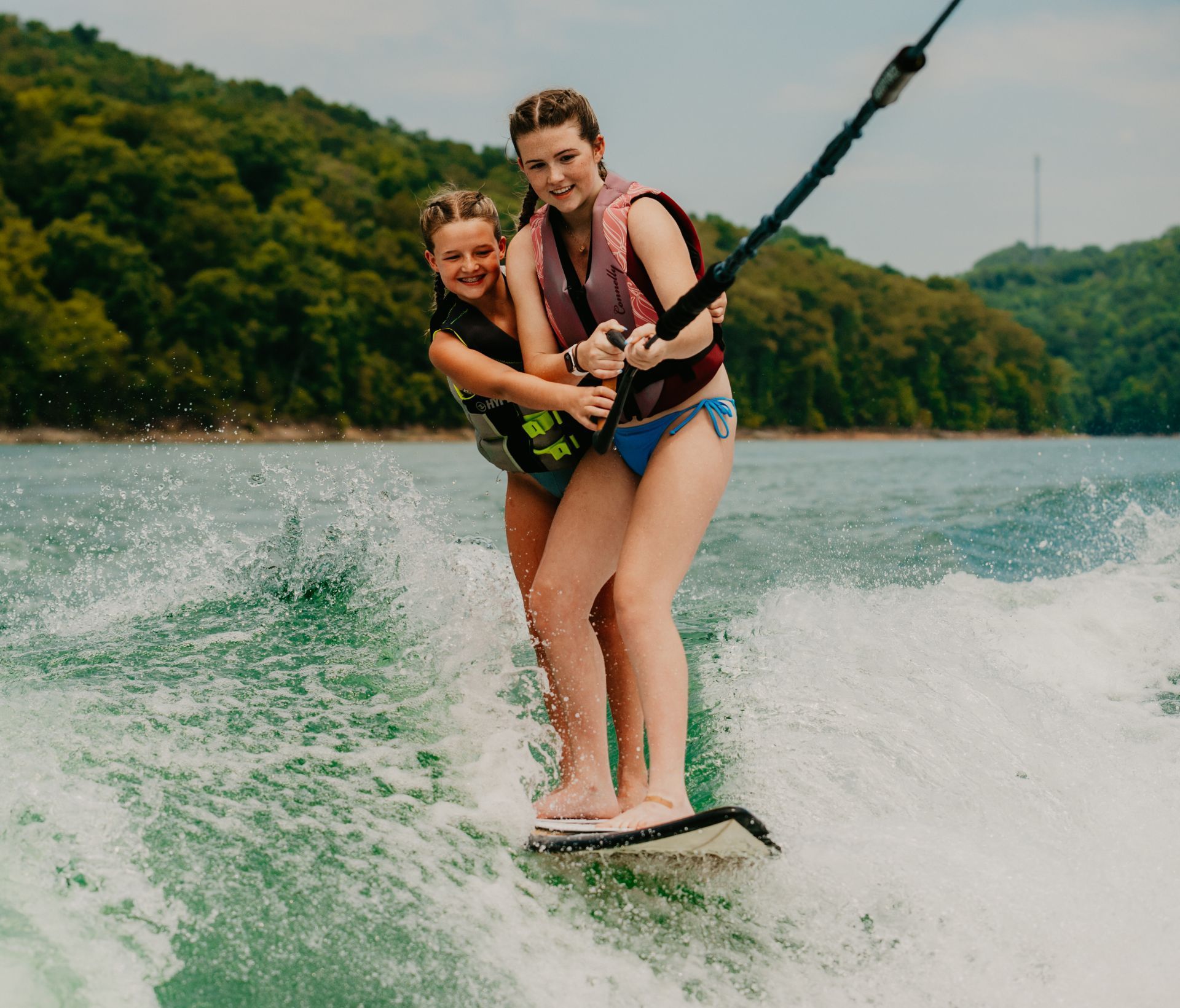 Two girls are riding a wakeboard on a lake