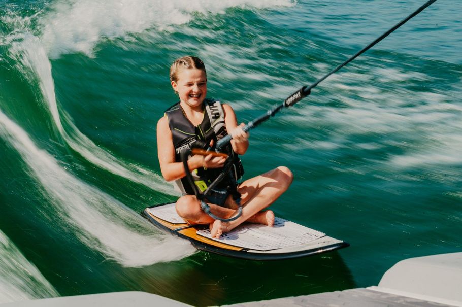 A young girl is riding a wave on a wakeboard