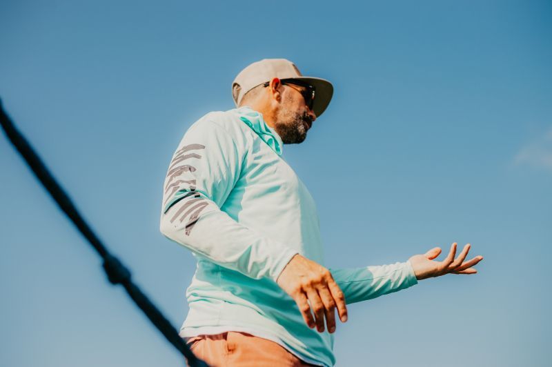 A man is standing on a boat with blue skies. 