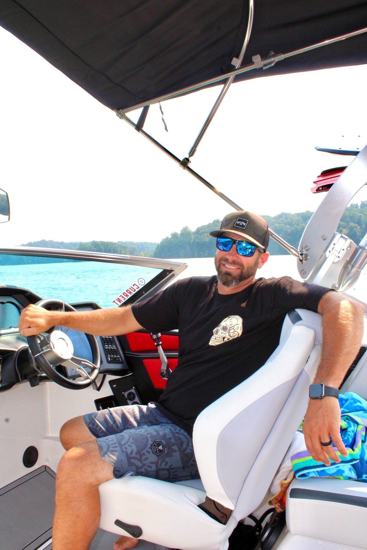 A man wearing sunglasses and a baseball cap is sitting on a boat.