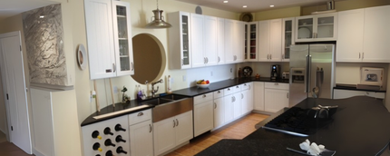 A kitchen with white cabinets and black counter tops.