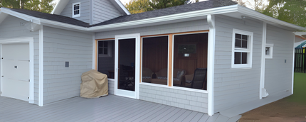 A small white house with a screened in porch and a grill.