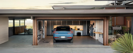 A blue car is parked in a garage next to a house.